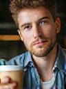 Junger Mann mit Tasse vor Laptop